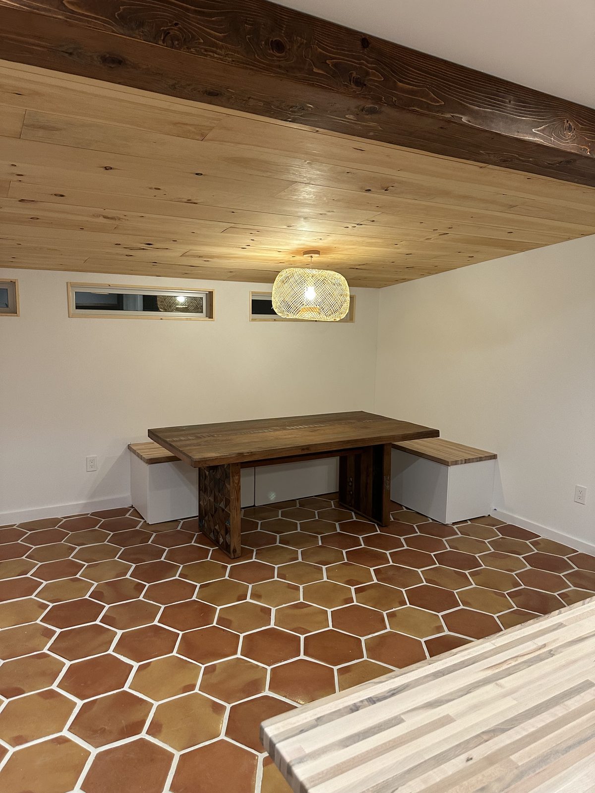 Dining room with a tongue-and-groove pine plank ceiling, an exposed stained beam, built-in perimeter benches and a matching wood table.