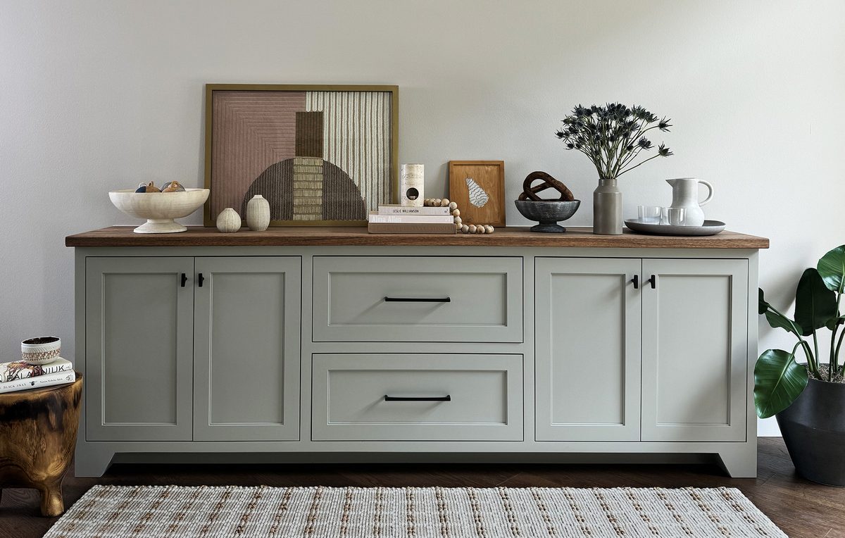 Built-in living room media console in painted sage cabinetry with a solid wood top and open display shelving.